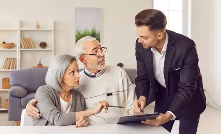 Older couple discussing a tablet with a man in a suit at home